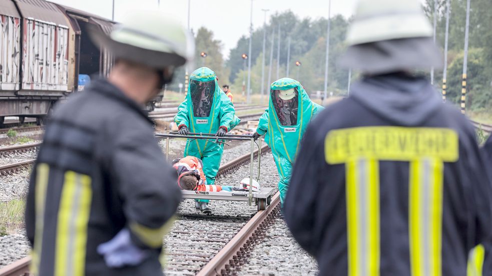 Feuerwehrleute in Schutzanzügen bringen einen Verletzten auf einem speziellen Gleistransportwagen aus dem Gefahrenbereich. Dabei handelt es sich um eine Übung, bei realen Einsätzen würden wir Fotos dieser Art nicht zeigen. Foto: Hock