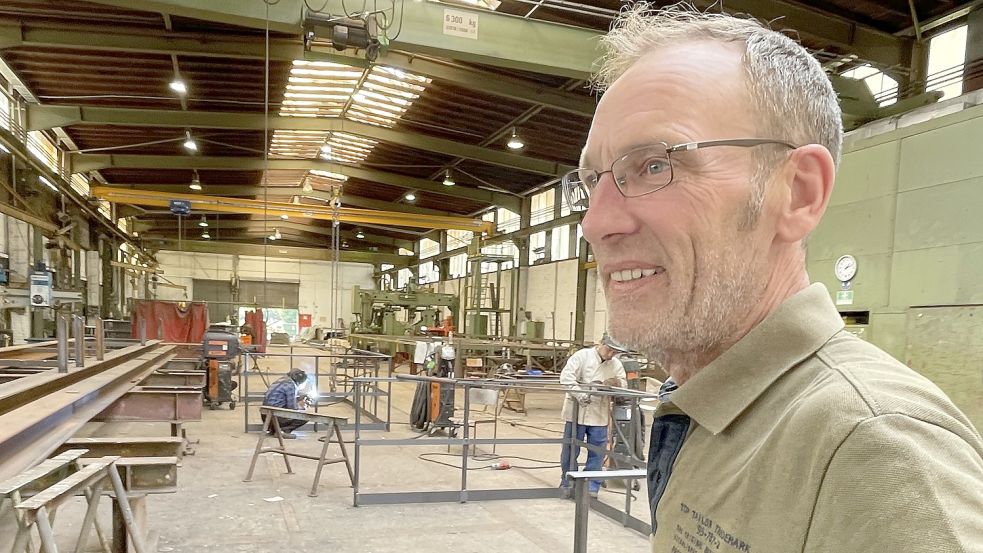 Frank Steffens steht in der Produktionshalle der Emder Stahlbaufirma Klaas Siemens. Im Hintergrund werden Geländerteile zusammengeschweißt. Foto: Päschel