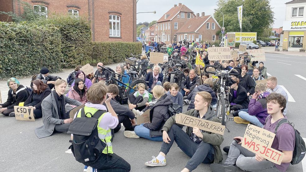 Organisator Tex Stoffer fordert die Demonstranten auf, sich hinzusetzen. Auch die Fahrradfahrer steigen von ihren Rädern ab. Fotos: Löschen