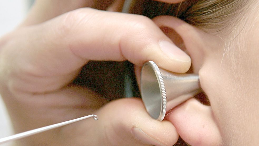 Ein Hals-Nasen-Ohren-Arzt untersucht in seiner Praxis das Ohr beziehungsweise den Gehörgang einer Patientin. Foto: Frank Leonhardt/DPA