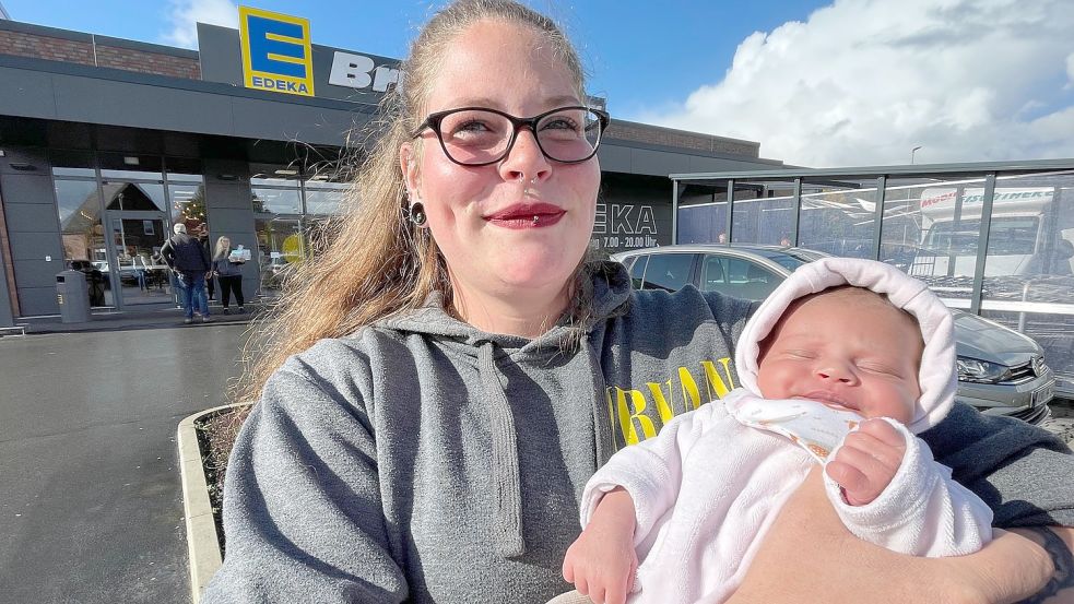 Laura Tönjes hält ihre acht Tage alte Tochter Lyn auf dem Parkplatz in Pewsum, wo sie das Mächen gesund zur Welt gebracht hatte. Foto: Päschel