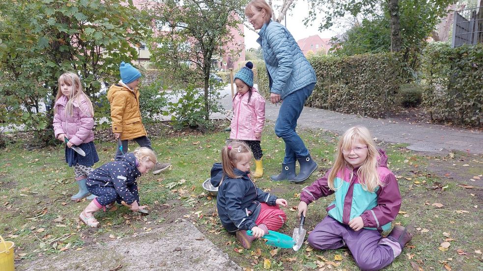 Jamie-Lee (von rechts), Edona und Anja machen sich am Boden an die Arbeit und buddeln Blumenzwiebeln vor der Kita Schwabenstraße ein. Fotos: Hanssen