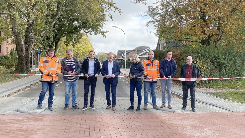 Vertreter der Stadt Aurich und Bürgermeister Horst Feddermann (Vierter von links) zerschneiden das Absperrband und zelebrieren damit die Fertigstellung der Popenser Straße. Fotos: Löschen