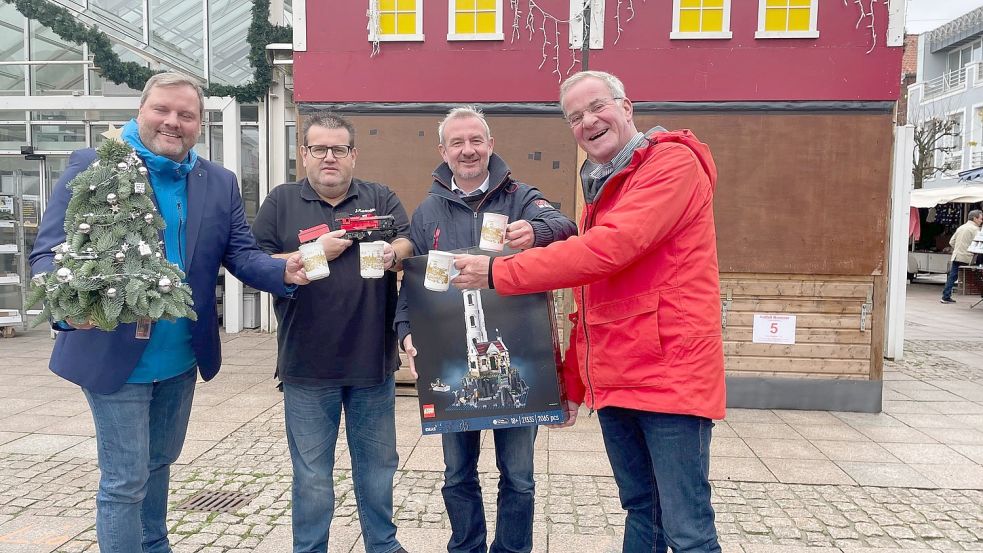 Auch in diesem Jahr gibt es wieder Auricher Weihnachtszauber-Becher. Mit denen stießen Udo Hippen (von links), Jens Coordes, Marco Bordasch und Johann Stromann schon mal auf einen Erfolg der Veranstaltung an. Foto: Boschbach
