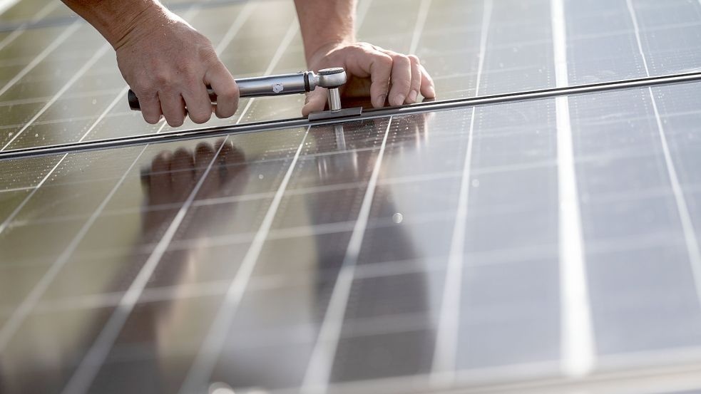 Mitarbeiter einer Firma montieren Photovoltaikmodule auf dem Dach eines Wohnhauses. Foto: Murat/dpa