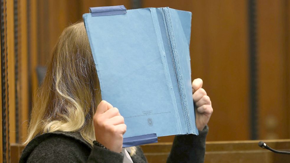 Die Angeklagte deckt im Landgericht ihr Gesicht mit einem blauen Ordner ab. Rund acht Monate nach der Entdeckung eines getöteten Babys in Mönchengladbach beginnt der Prozess gegen die Mutter des Kindes. Foto: David Young/dpa