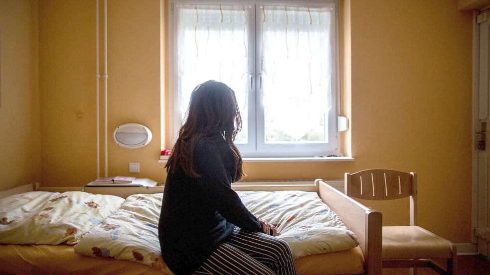 Eine Frau sitzt in einem Frauenhaus auf einem Bett. Foto: Maja Hitij/dpa