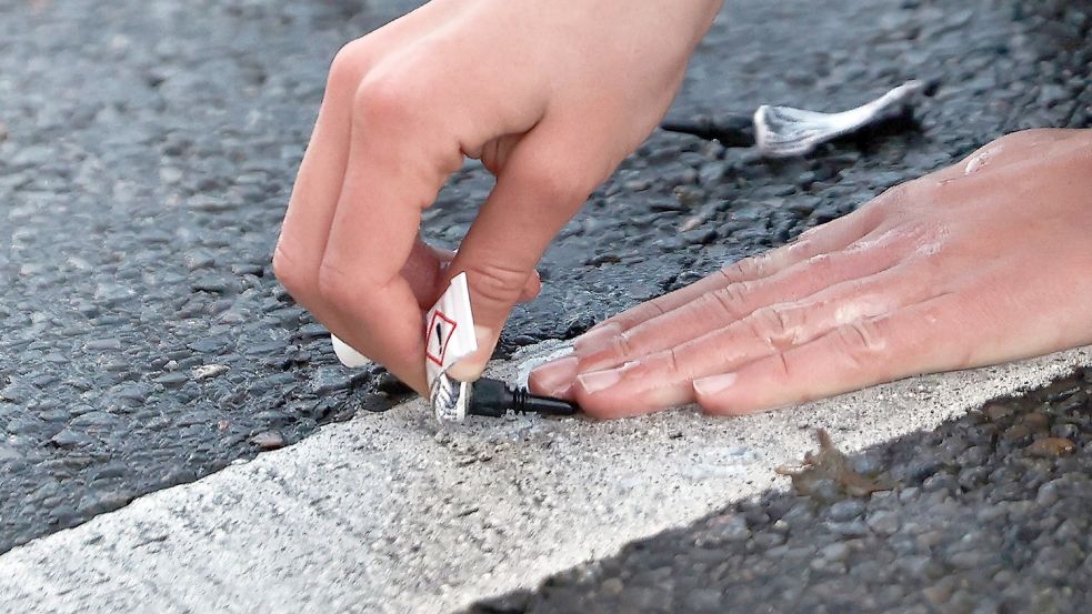 Ein Aktivist von „Letzte Generation“ klebt seine Hand mit Sekundenkleber auf der Straße in Berlin während einer Sitzblockade fest. Foto: Carsten Koall/dpa
