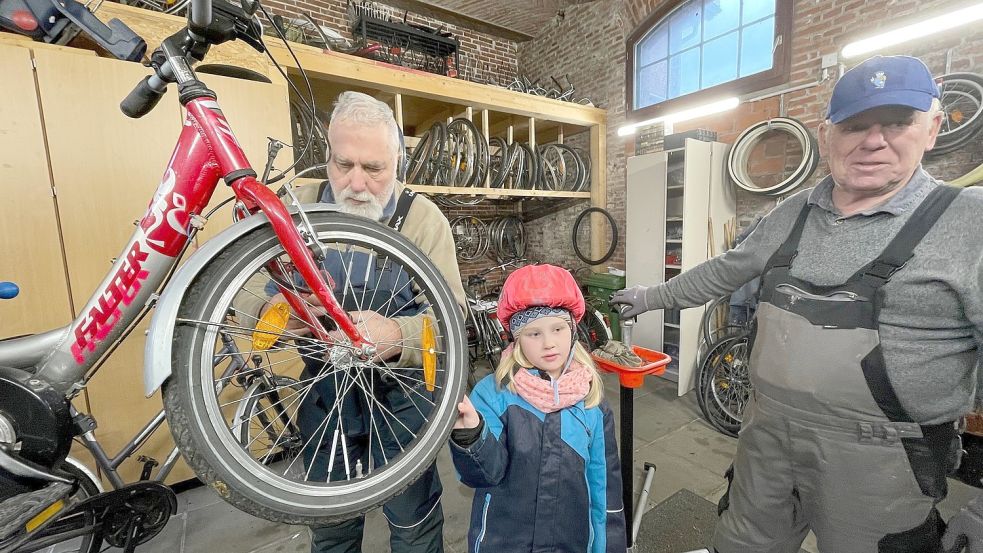 Johanna schaut in der Fahrrad-Werkstatt fasziniert zu, wie sich gleich zwei Männer, nämlich Rolf Ruder (links) und Herbert Egden, um ihr Fahrrad kümmern. Foto: Boschbach