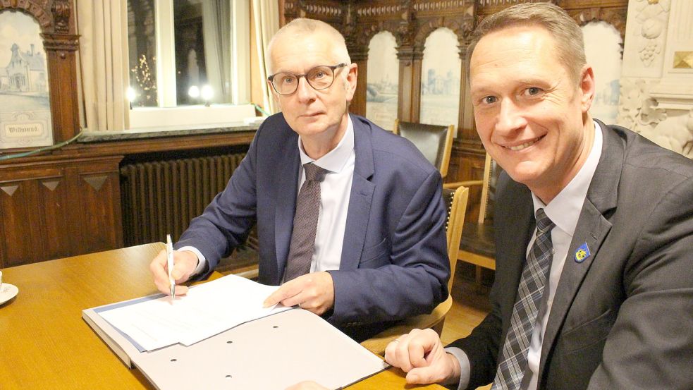 Kai Schasse (links) unterschreibt seinen Vertrag als Geschäftsführer des Wittmunder Krankenhauses. Landrat Holger Heymann freut sich. Foto: Oltmanns