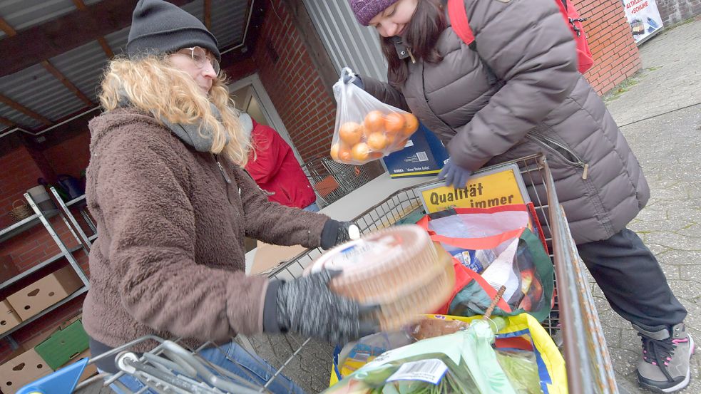 Seit Corona wurde die Ausgabestelle der Spieskamer in Rechtsupweg nach draußen in den Hof verlegt. Die ehrenamtliche Helferin Simone Janssen-Weerts (links) packt Lebensmittel in den Wagen einer Kundin. Fotos: Ortgies