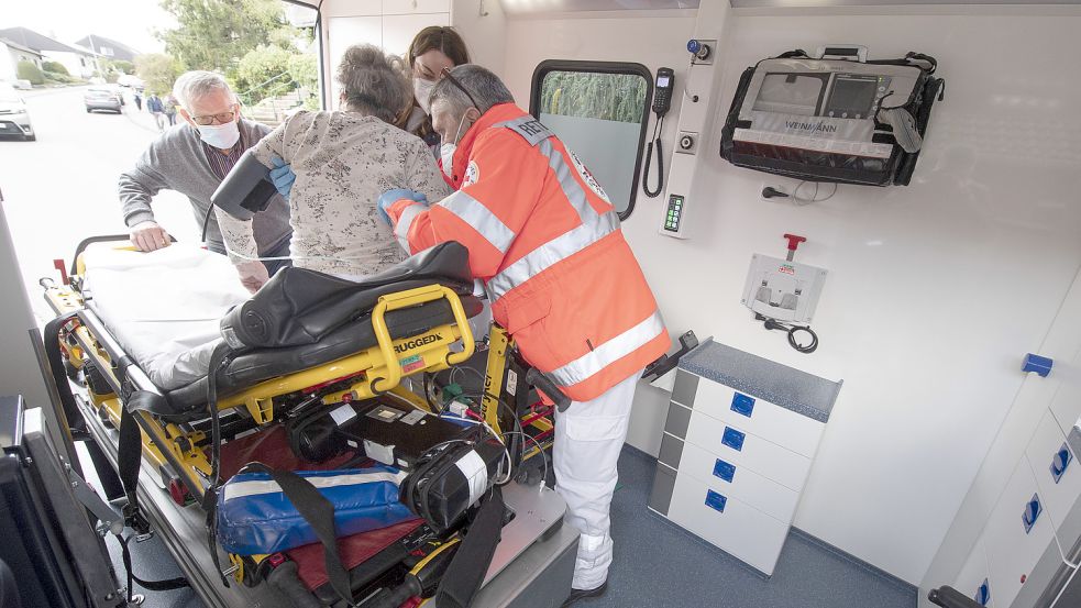 Gemeinsam mit einem Helfer bringen Notfallsanitäter des Deutschen Roten Kreuzes eine Seniorin nach einem Schlaganfall in einen Rettungswagen. Symbolfoto: Roessler/dpa