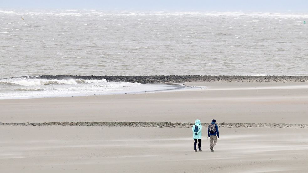 Spaziergänger am Strand der Insel Norderney. Im Oktober ist die Zahl der Gäste auf den Ostfriesischen Inseln zurückgegangen. Foto: Bartels/dpa