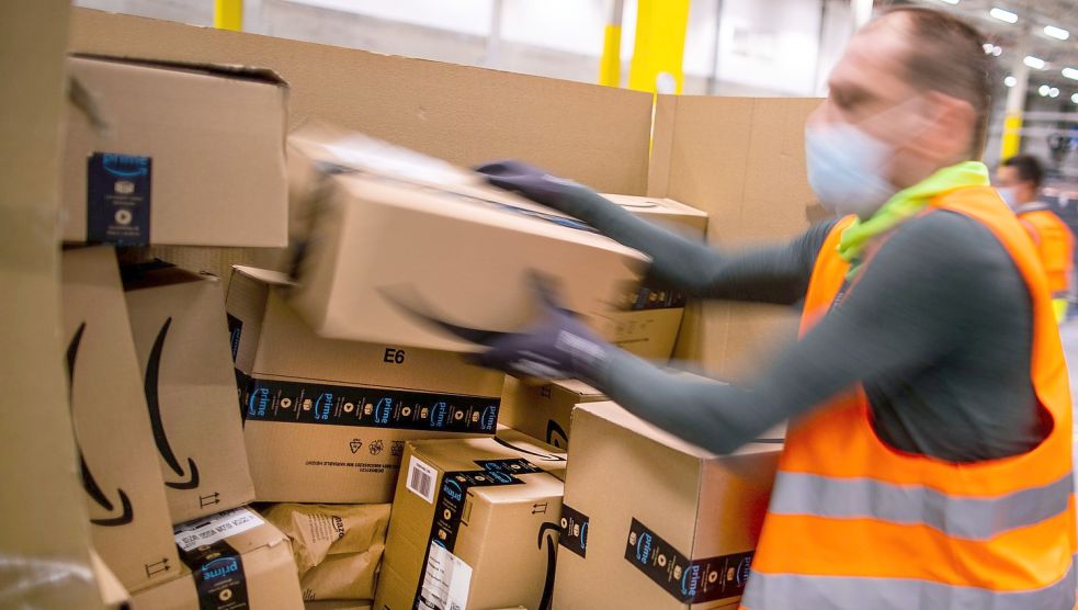 Ein Mitarbeiter sortiert an einem Transportband in einem Verteilzentrum des Online-Händlers Amazon Paketsendungen für die Auslieferung. Foto: Jens Büttner/DPA