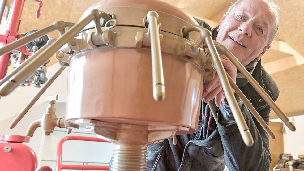 Karlheinz Eschen mit einer Maschine, mit der der Schnaps abgefüllt wurde. Sie ist demnächst im Torf- und Siedlungsmuseum in Wiesmoor zu sehen. Foto: Ortgies