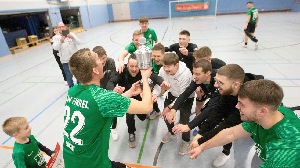 Firrels André Lücht reckte den Siegerpokal vor seinen Mitspielern in die Höhe. Doch Offensivmann Manuel Suda (oben rechts) wollte offenbar nicht dabei sein.Fotos: Doden, Emden