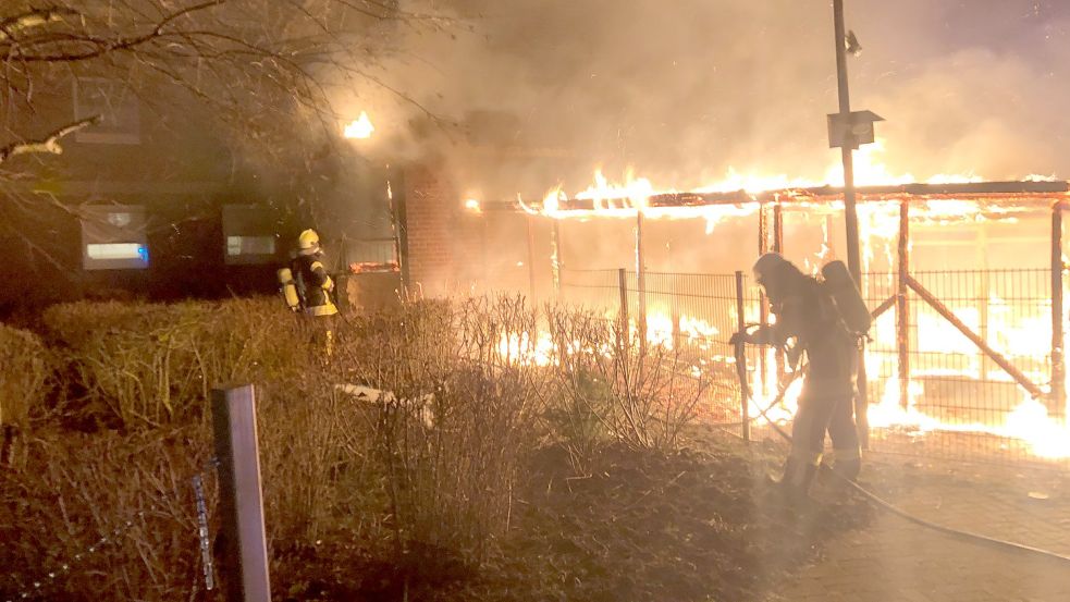 Einsatzkräfte der Feuerwehr gehen gegen die Flammen am Carport vor. Foto: Feuerwehr Emden