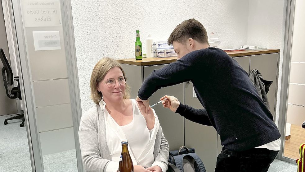 Impfen mit Bier: Sandra Bröske hat im Landkreis Wittmund die erste und die letzte Corona-Impfung bekommen. Im Bild bekommt sie gerade die letzte zum Ende der öffentlichen Impfungen im Dezember 2022. Während der Abschlussfeier, wie am Bier im Hintergrund zu erkennen ist. Foto: Privat