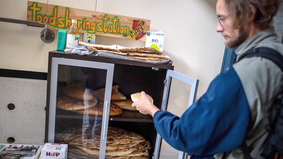 Ein Mann holt ein Brötchen aus einem Schrank der Foodsharing-Station in einem Gemeindezentrum in Bremen. Foto: Schuldt/DPA