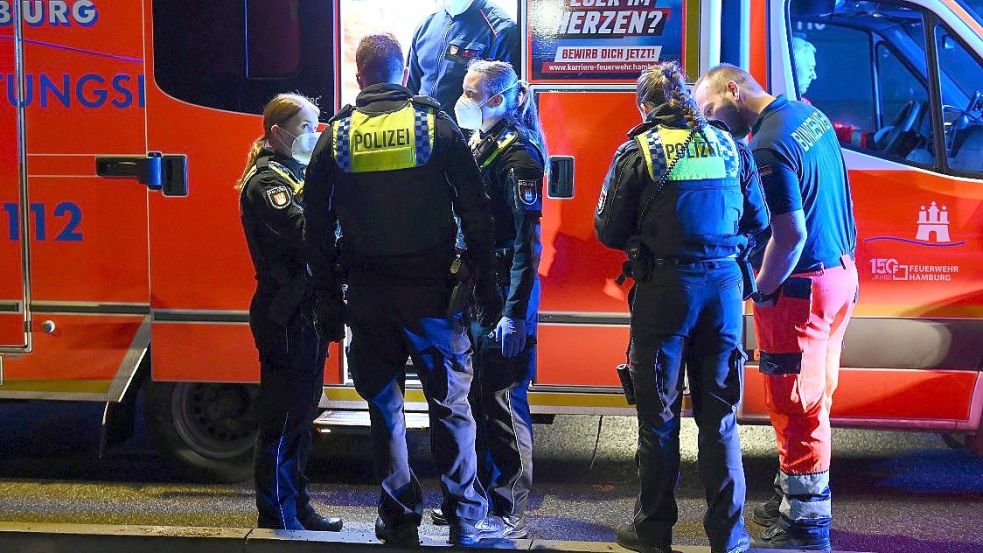 Rettungssanitäter und Polizisten stehen an einem Rettungswagen. Die Polizei und der Rettungsdienst arbeiten oft eng zusammen. Foto: Jonas Walzberg/dpa