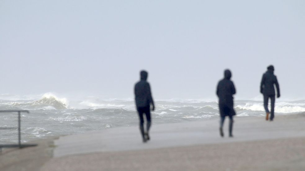 Wie hier auf Norderney peitschte der Wind die Nordsee auf. Spaziergänger hielt das nicht ab. Foto: Volker Bartels/dpa