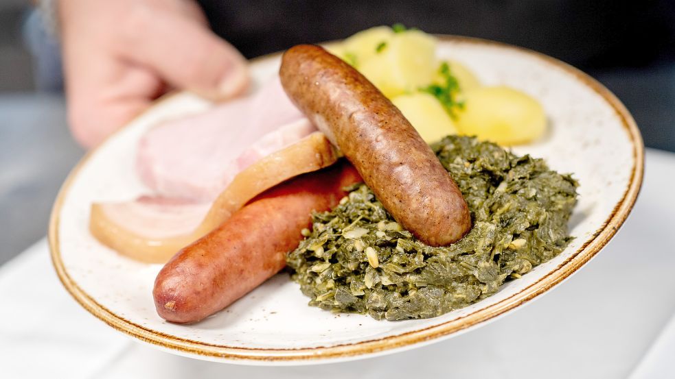 So kennt man den Grünkohl: mit den traditionellen Beilagen Salzkartoffeln, Kochwurst, Pinkel und Kasseler. Foto: Dittrich/DPA