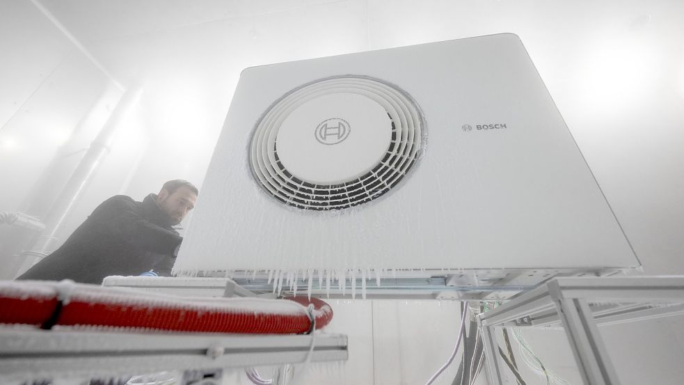 Ein Mitarbeiter der Bosch Thermotechnik GmbH öffnet in einer Klimakammer das Gehäuse einer Bosch-Wärmepumpe. Foto: Marijan Murat/dpa