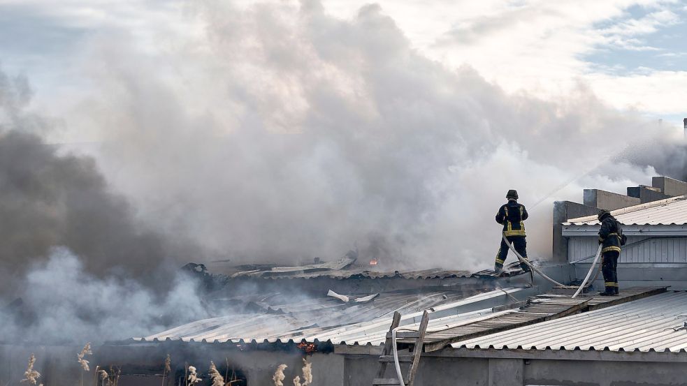 Feuerwehrleute des staatlichen ukrainischen Katastrophenschutzes löschen ein Feuer, das nach Beschuss eines Industriegebiets in Cherson ausgebrochen ist. Foto: Libkos/AP/dpa