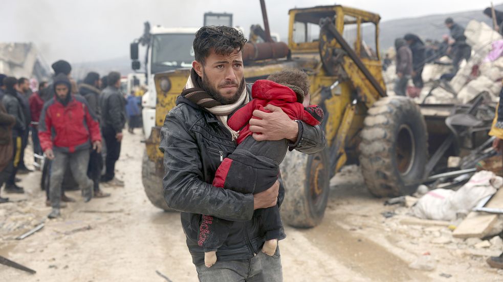 Ein Mann trägt im syrischen Besnia die Leiche eines kleinen Erdbebenopfers. Foto: Alsayed/AP/DPA