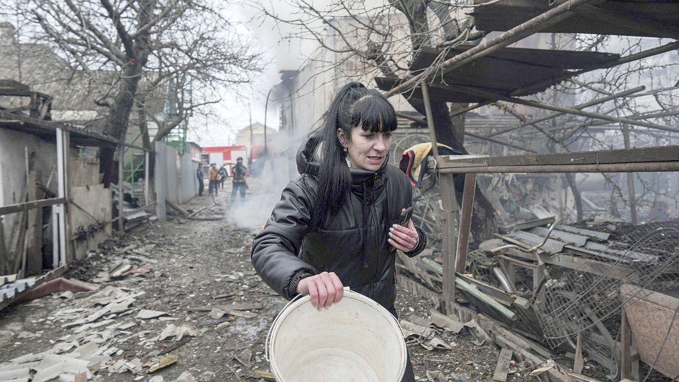 Auch aus der stark umkämpften Stadt Mariupol in der Ukraine kamen Flüchtlinge nach Wittmund. Das Bild entstand am 24. Februar 2022 in Mariupol und zeigt eine Frau, die nach russischem Beschuss an den Trümmern vorbeigeht. Foto: Maloletka/AP/dpa