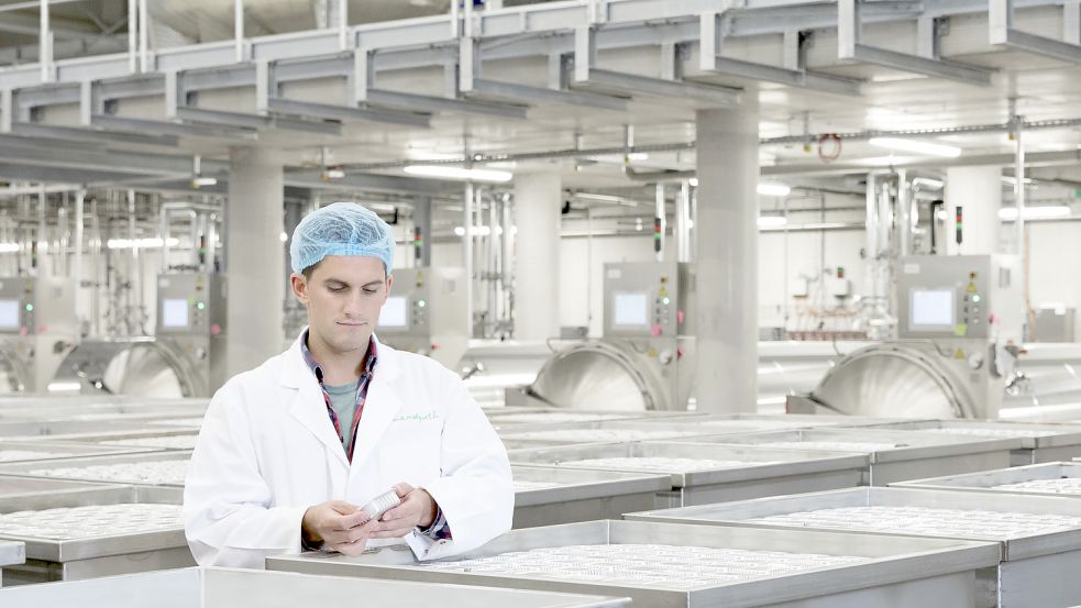 Ein Mitarbeiter an den Autoklavenkörben, mit denen das Tierfutter nach der Abfüllung zum Sterilisieren in den Autoklaven (im Hintergrund) transportiert wird. Foto: Hagen/Landguth