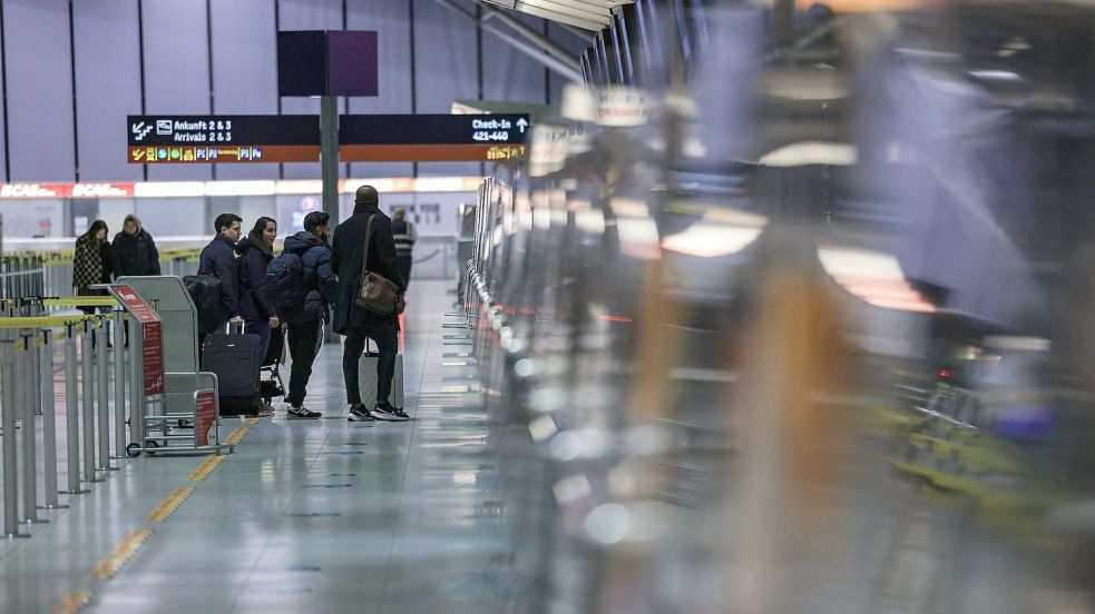 Reisende stehen am Flughafen Köln/Bonn vor einem Schalter. Foto: Oliver Berg/dpa