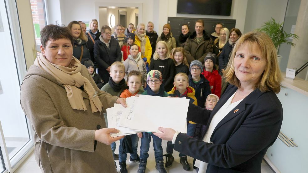 Melanie Remijn (vorne links) übergibt zusammen mit Eltern und Kindern aus Loquard gesammelte Unterschriften an die Krummhörner Bürgermeisterin Hilke Looden (parteilos). Foto: Hock