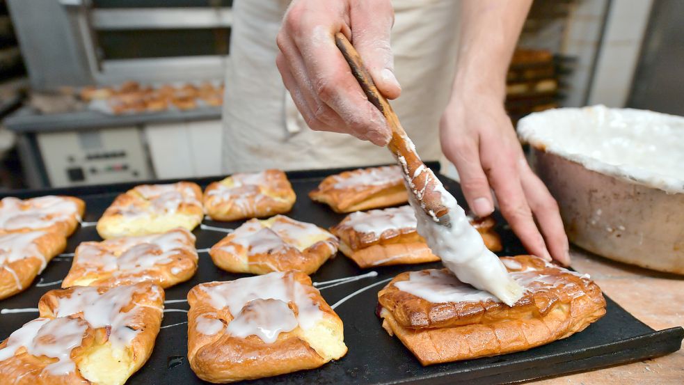 Ein Bäckermeister pinselt in Gotha Zuckerguss auf süßes Gebäck in seiner Backstube. Der junge Mann hat den Betrieb 2014 von seinem Vater übernommen. Fehlende Nachfolger können für immer mehr mittelständische Firmen in Deutschland einer Umfrage zufolge das Aus bedeuten. Foto: Schutt/DPA-Zentralbild/DPA