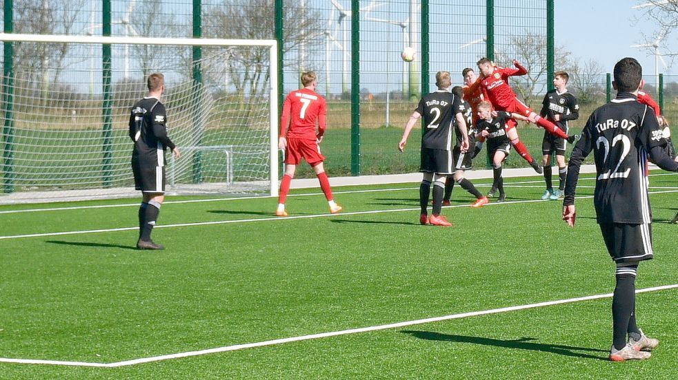 Das Tor zum 1:1: Pewsums Hauke Ulferts (rechts in Rot) kommt per Kopf an den Ball, TuRa-Keeper Hendrik Gossmann (links daneben) segelt vorbei. Fotos: Wagenaar