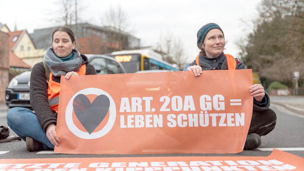 Auf Straßen sitzende Aktivisten mit orangenen Warnwesten sind ein Wiedererkennungsmerkmal der Letzten Generation. Foto: IMAGO IMAGES/Eibner