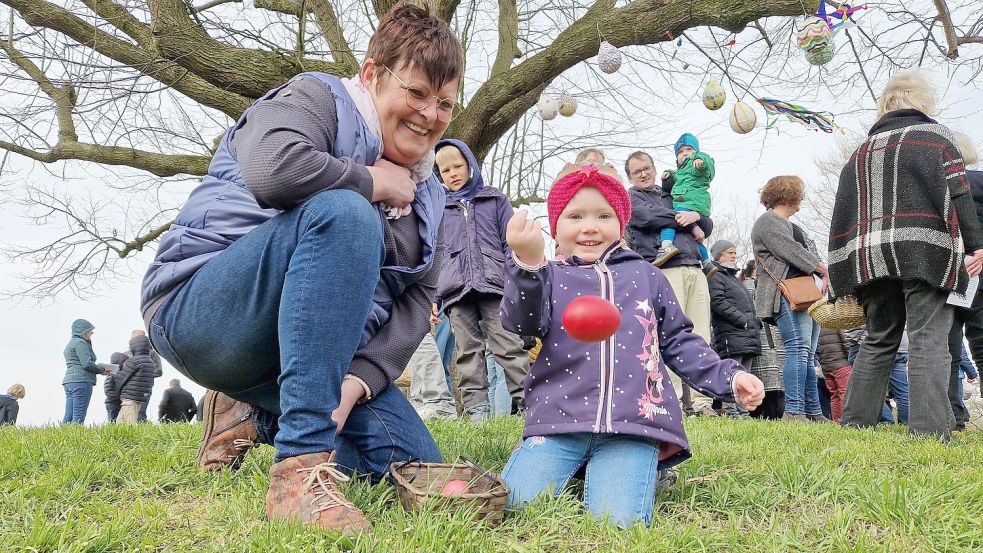 Agnes Wienberg aus Leer zeigte ihrer Engeltochter Maila das Eiertrüllen. Die Dreijährige hatte Spaß zu beobachten, wie die bunten Eier den Plytenberg herunterkullerten. Foto: Gettkowski