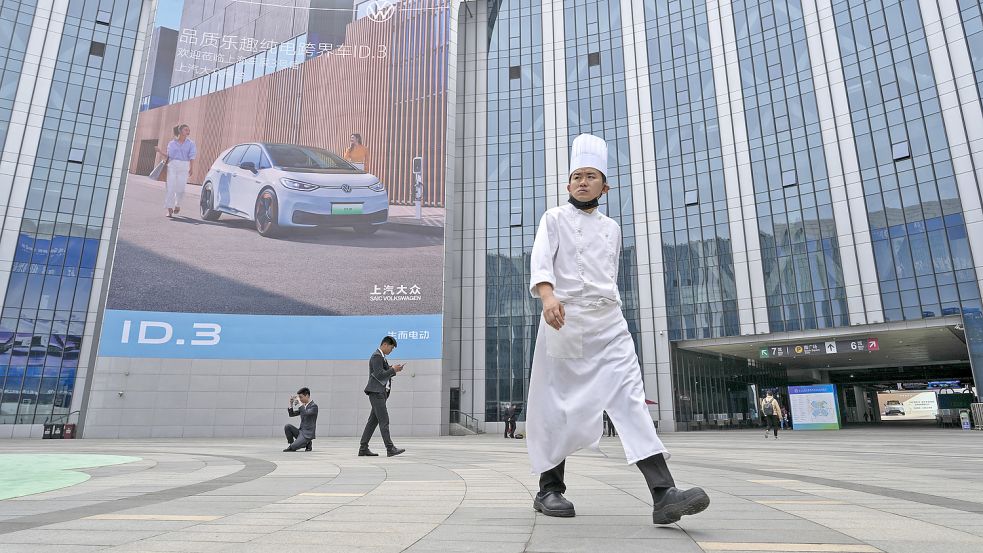 Ein Koch und Arbeiter halten sich in der Nähe einer Werbung für den Volkswagen ID.3 auf, die im National Exhibition and Convention Center während der Auto Shanghai 2023 in Shanghai ausgestellt ist. Globale und chinesische Autohersteller wollen diese Woche auf der Auto Shanghai mehr als ein Dutzend neue Elektro-SUVs, Limousinen und Muscle Cars vorstellen. Foto: Ng Han Guan/AP/DPA