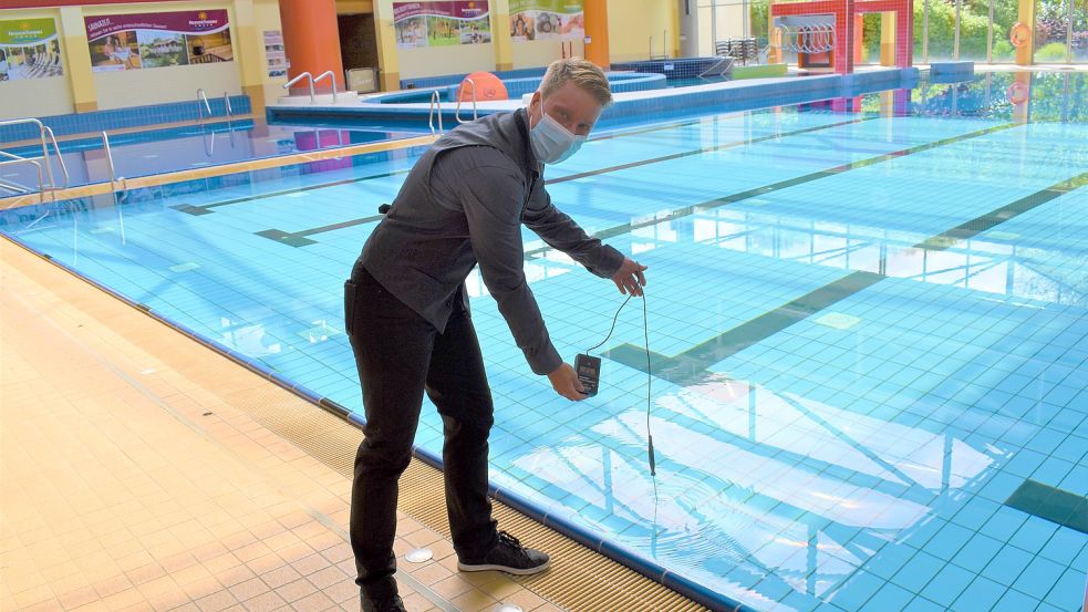 Marc Schneidereit misst die Temperatur des Badewassers in der Friesentherme: Zu dem Zeitpunkt - das war 2021 nach einer längeren Sanierung - betrug sie etwa 25 Grad. Jetzt sind es 26 Grad im großen Becken. Foto: Hanssen/Archiv