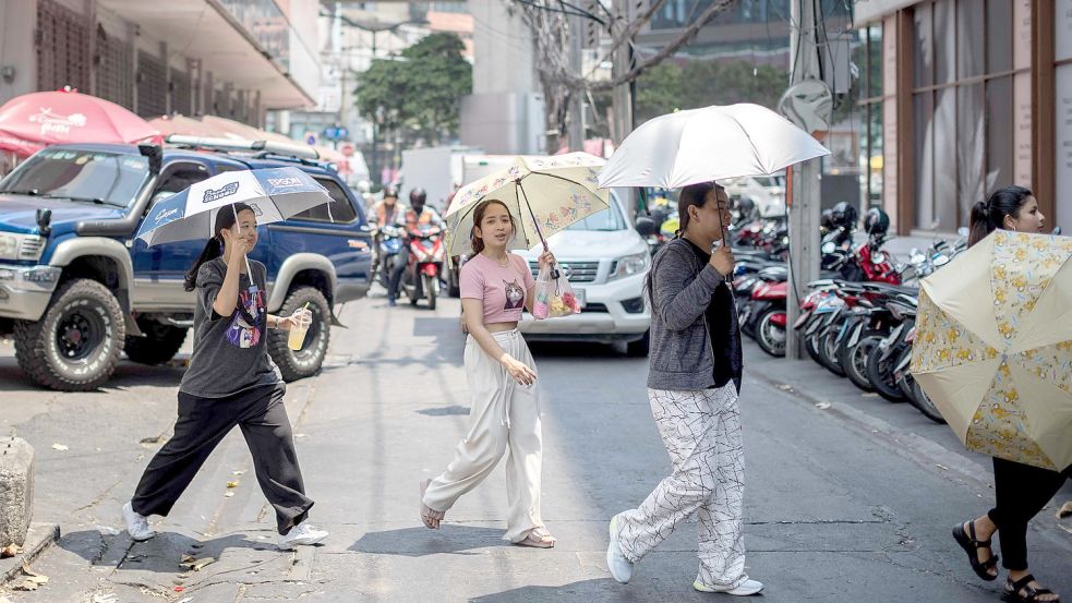 Hitzewelle in Thailand: Schwitzende Menschen auf einer Straße in Bangkok schützen sich mit Schirmen vor der Sonne. Foto: Jack Taylor/AFP