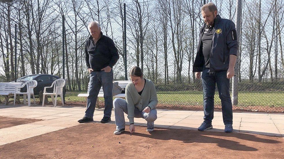 Ich (Denise Cordes, Mitte) versuche die Murmel in die Kuhle zu befördern. Der Ehrenvorsitzende Jörg Bünting (links) beäugt mich als Schiri, der Erste Vorsitzende Wilhelm Reunitz ist mein Gegner. Foto: Tanja Janssen, TuS Middels