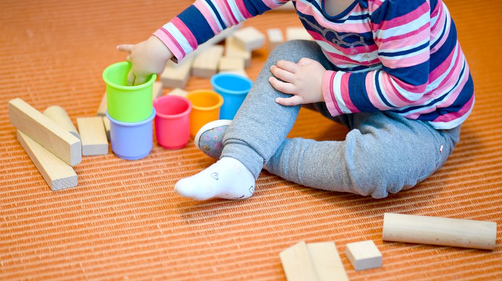 Ein Mädchen spielt in einer Kita mit bunten Bechern und Bauklötzen. Vielerorts in Niedersachsen fehlt es in den Einrichtungen an Personal. Foto: Anspach/DPA/Archiv