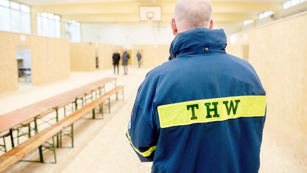 Offensichtlich gut vorbereitet: Ein Mitarbeiter des Technischen Hilfswerks (THW) steht in einer zur Flüchtlingsunterkunft umgebauten Sporthalle auf dem Gelände der ehemaligen Blücher-Kaserne. Der Landkreis Aurich hat Mitte/Ende November mehrere neue Flüchtlingsunterkünfte vorgestellt, die in Zukunft sowohl von afghanischen Ortskräften mit ihren Familien als auch von ukrainischen Geflüchteten genutzt werden sollen. Foto: Dittrich/dpa