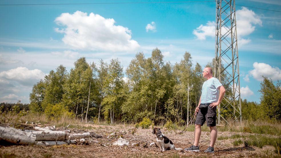 Rund um einen Strommast der Avacon-Hochspannungstrasse, die übers Ottermeer führt, ist eine Fläche gerodet worden. „Hier wird keiner gestört, man müsste das Areal eigentlich nur umzäunen“, findet Diedrich Kleen – im Bild mit seinem Terrier „Milhouse“. Gewollt scheint die Fläche nicht. Foto: Cordsen