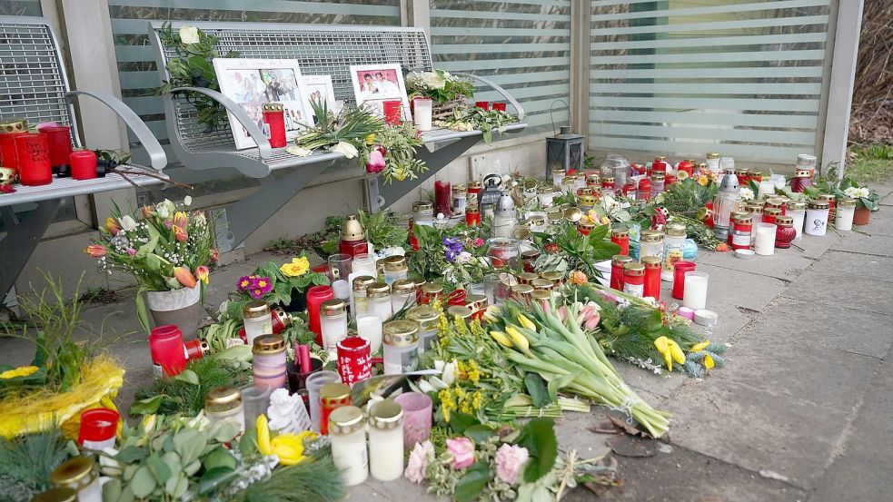 Kerzen und Blumen stehen und liegen im Bahnhof Brokstedt in einem Wartehäuschen. Foto: Marcus Brandt/dpa