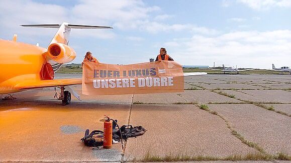 „Euer Luxus, eure Dürre“ steht auf dem Plakat, das die Aktivisten der „Letzten Generation“ zusätzlich zu der Farbe an dem Privatjet auf Sylt angebracht haben. Foto: Letzte Generation