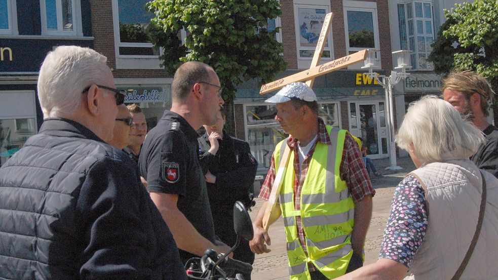 Ein Polizeibeamter erklärt Dirk Harms (in gelber Weste), dass er die Gegenkundgebung nicht stören darf. Fotos: Luppen