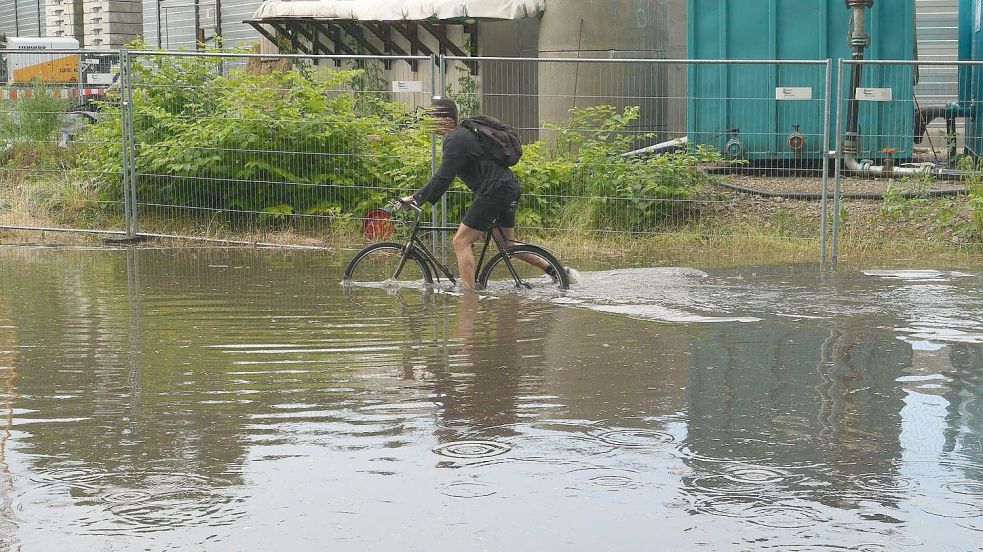 Ein Radfahrer kurbelt sich durch die Wassermassen in Hamburg-Bahrenfeld. Foto: Danfoto