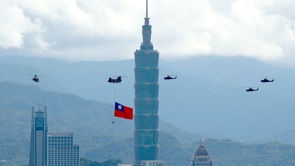 Ein Militärhubschrauber zieht eine riesige Taiwan-Fahne hinter sich her und fliegt vor den Feierlichkeiten des Nationalfeiertag am Hochhaus „Taipei 101“ vorbei. Foto: dpa/ZUMA Wire/Daniel Ceng Shou-Yi