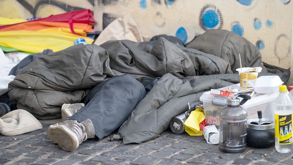Eine Person schläft unter einem Schlafsack in der Innenstadt von Stuttgart. Auch in Emden wird die Armut immer sichtbarer. Foto: Marijan Murat/dpa